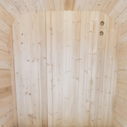 Interior view of a light natural cedar sauna with vertical wood paneling and two circular vents.