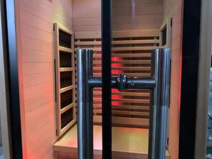 Lumin One infrared sauna with light Canadian Hemlock interior, black glass door, and stainless steel handle.