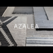 Surya Azalea AZA-2325 hand-woven rug samples in various white, gray, and black recycled PET yarn patterns.
