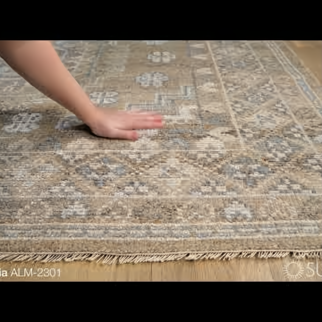 Hand-knotted Surya Almeria rug with multi-color geometric pattern, fringe, and a hand touching the low pile.