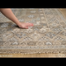 Hand-knotted Surya Almeria rug with multi-color geometric pattern, fringe, and a hand touching the low pile.