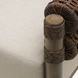 Close-up of Surya Porta Swivel Chair with beige Sunbrella cushion, brown handwoven PE wicker, and wood-look arm.