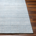 Light blue Surya Fresno area rug with subtle textured stripes on a dark wood floor.