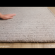 Hand-woven Surya Azalea AZA-2315 rug, light gray recycled PET yarn, with a hand touching its textured surface.