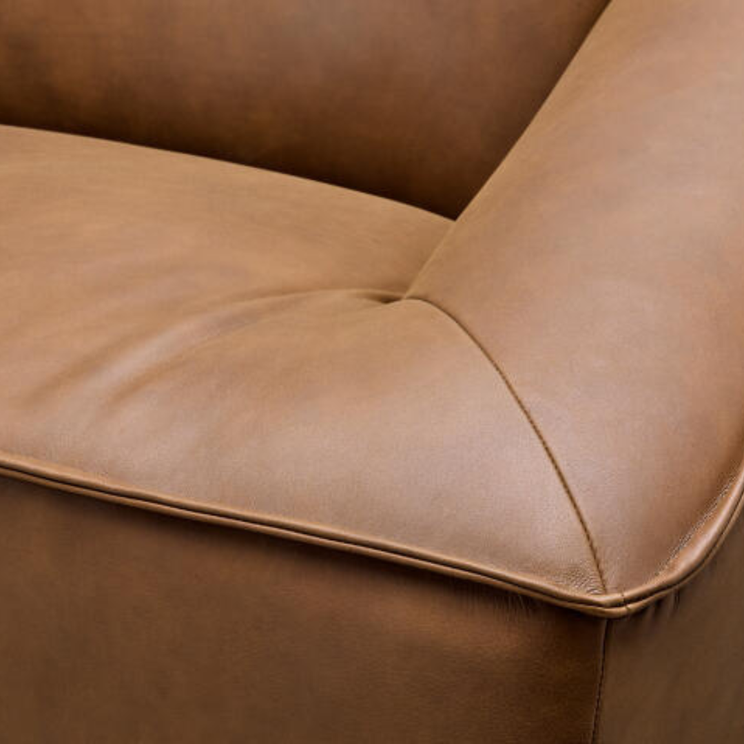 Close-up of a brown leather Surya Alba sofa with cushioned seating and refined piping.