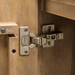 Close-up of a silver hinge on the brown stained mango wood Surya Silas Cabinet.