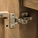 Close-up of a silver hinge on the brown stained mango wood Surya Silas Cabinet.