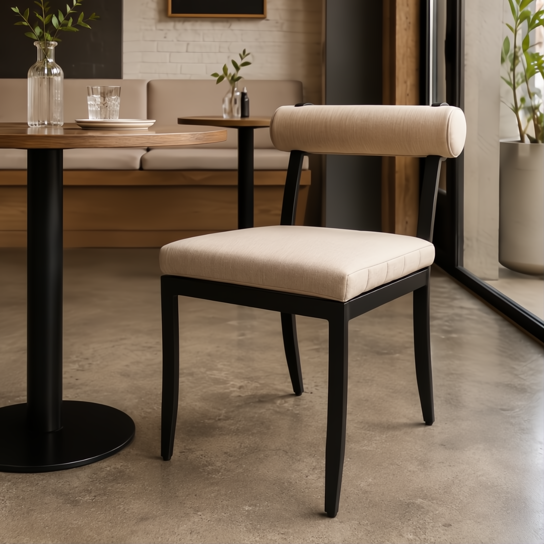Surya Antibes Dining Chair with black aluminum frame and beige Sunbrella® upholstery in a modern cafe setting.