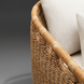 Close-up of a woven rattan outdoor sofa with light cream cushions.