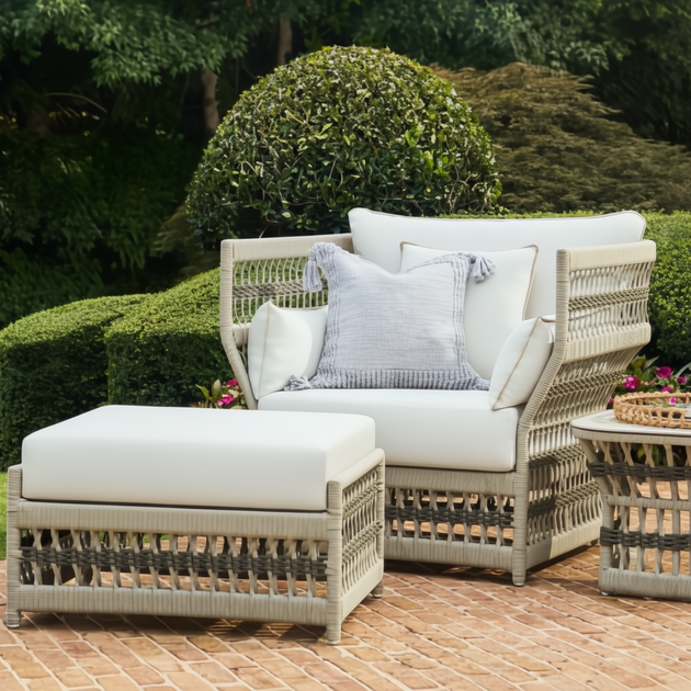 Cream Surya Winder accent chair with Sunbrella cushions, matching ottoman, and side table on a patio.