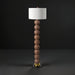 Surya Algarve 62" brown and gold floor lamp with a stacked resin body, black iron base, and white linen shade.
