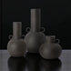 Set of three dark gray ceramic decorative vases with sculptural, globally inspired designs.