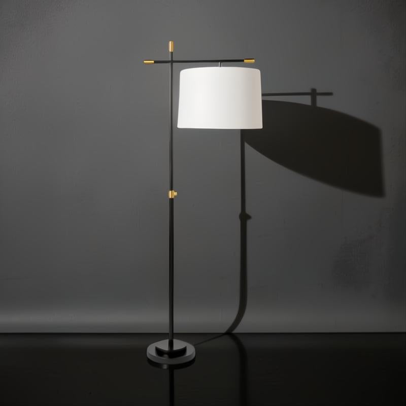 Modern black and gold sculptural floor lamp with an ivory linen shade, casting a soft glow.