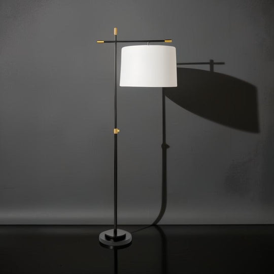 Modern black and gold sculptural floor lamp with an ivory linen shade, casting a soft glow.
