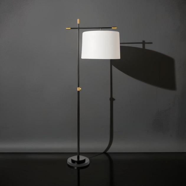 Modern black and gold sculptural floor lamp with an ivory linen shade, casting a soft glow.
