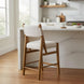 Surya Bergene light beige upholstered counter stool with brown rubber wood frame and angular backrest.