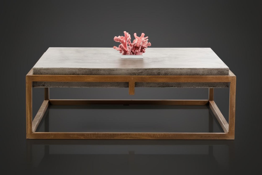 Industrial-modern concrete coffee table with a sleek metal frame, topped with pink coral decor.