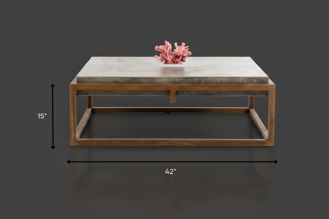 Industrial-modern concrete coffee table with a gray top and a bronze metal frame. 42" long, 15" high.