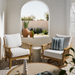 Two outdoor Surya Cape Town swivel chairs with wheat aluminum frames and white Sunbrella cushions, one with a striped pillow.