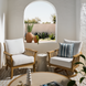 Two outdoor Surya Cape Town swivel chairs with wheat aluminum frames and white Sunbrella cushions, one with a striped pillow.