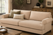 Surya Elowena sofa in light beige polyester with rolled arms, dark wood legs, and two decorative pillows.