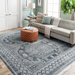 Surya Almeria low pile area rug with black, gray, beige, and blue geometric pattern in a living room.