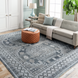 Surya Almeria low pile area rug with black, gray, beige, and blue geometric pattern in a living room.