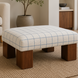 Surya Mirava Ottoman with a checkered polyester cover, polyurethane foam cushion, and brown stained rubber wood base.