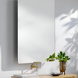 Modern rectangular mirror with rounded corners, a gold faucet, and a plant in a bronze pot.