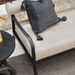 Surya Antibes outdoor sofa with beige Sunbrella upholstery, black aluminum frame, and a dark gray throw pillow.