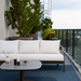 Surya Daniella outdoor sofa with white Sunbrella cushions and gray aluminum base on a modern balcony.