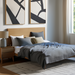 A bedroom with a wooden bed, grey bedding, and two black and white abstract wall art panels.