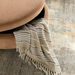 Brown and peach upholstered storage ottoman with a striped throw blanket partially visible.