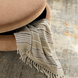 Brown and peach upholstered storage ottoman with a striped throw blanket partially visible.