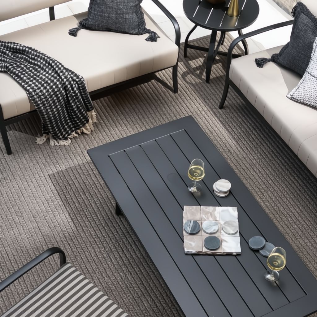 Surya Antibes 60-inch black powder-coated aluminum outdoor coffee table with slatted top, surrounded by patio furniture.