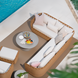Marvella sectional with light brown woven base, white cushions, and pink pillows on a patio by a pool.