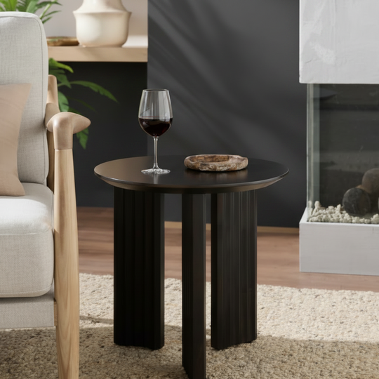Blackened mango wood round end table with zigzag fluted legs and a beveled edge top.