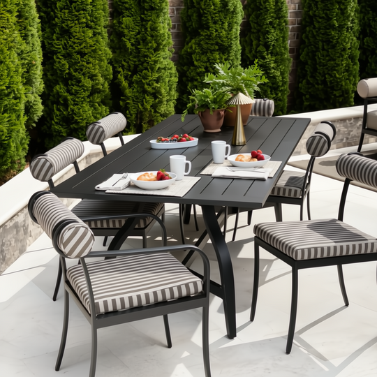 Black aluminum Surya Antibes outdoor dining table with striped chairs, set for breakfast on a patio.