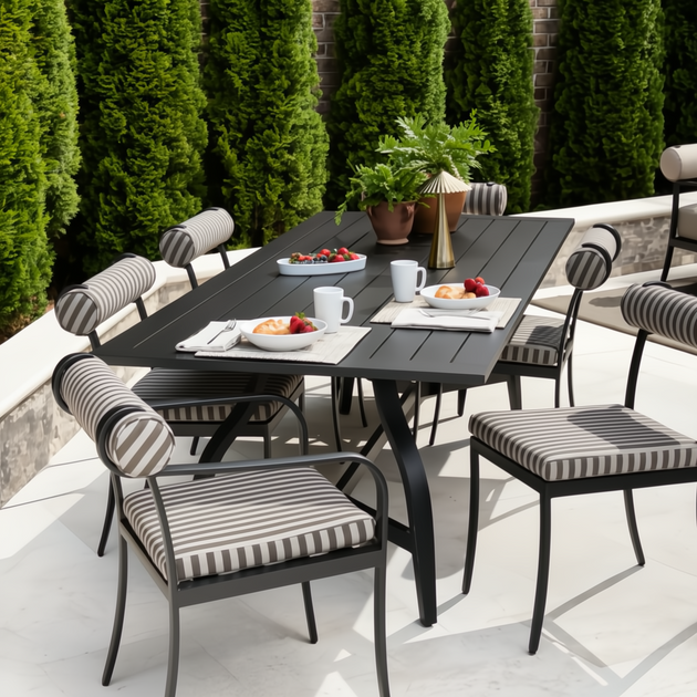 Black aluminum Surya Antibes outdoor dining table with striped chairs, set for breakfast on a patio.