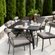 Black aluminum Surya Antibes outdoor dining table with striped chairs, set for breakfast on a patio.