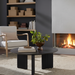 Blackened mango wood Surya Agnes round coffee table with a beveled top and zigzag fluted legs.