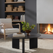 Blackened mango wood Surya Agnes round coffee table with a beveled top and zigzag fluted legs.