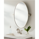 Surya Burnish oval wall mirror with antiqued metallic silver brass frame, vertically mounted above a sink.