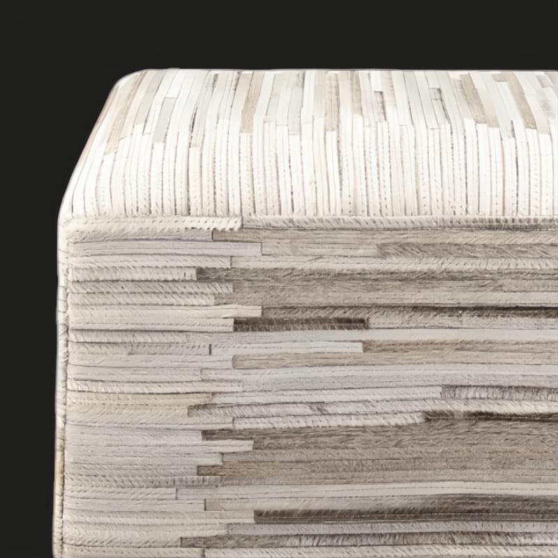 Modern square pouf upholstered in textured cream hair-on-hide, featuring horizontal and vertical stripe patterns.
