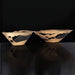 Two modern sculptural aluminum decorative accent bowls with a sleek metallic finish and black interiors.