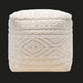 Surya Matthew Pouf, a cream knitted pouf with intricate beaded geometric patterns, on a dark background.
