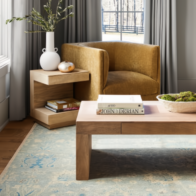 Brown lacquered mango wood Surya Coburn end table with open storage beside a gold chair.