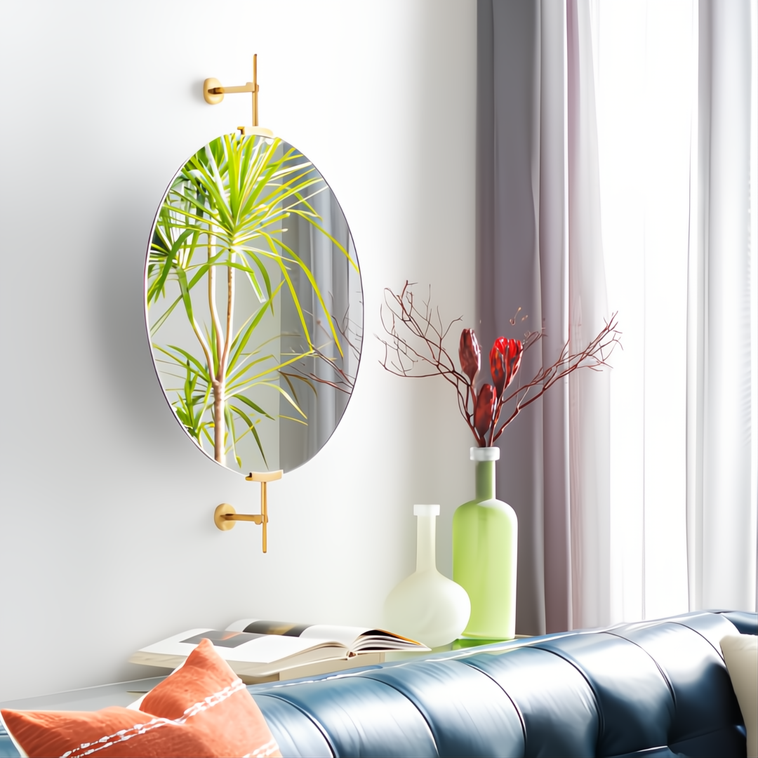 Modern oval mirror with gold-finished wall mounts, reflecting a plant, above a blue sofa and decorative vases.