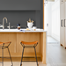 Brown lacquered leather counter stools with gray iron bases at a modern kitchen island.