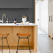 Brown lacquered leather counter stools with gray iron bases at a modern kitchen island.